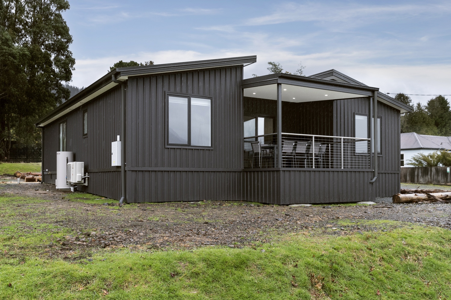 Exterior view of Tasbuilt Homes’ Hinterland Home in Maydena, Tasmania, showcasing a modern black-clad modular holiday home surrounded by lush greenery, designed for relaxation and outdoor living.