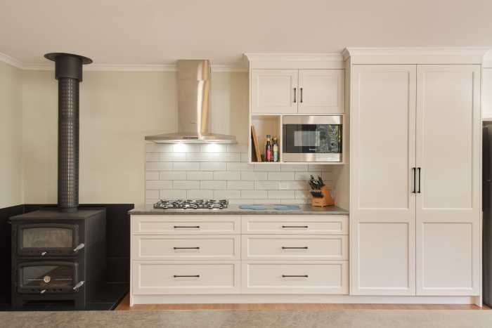Sleek Kitchen Storage with Tiled Splashback and Wood Heater