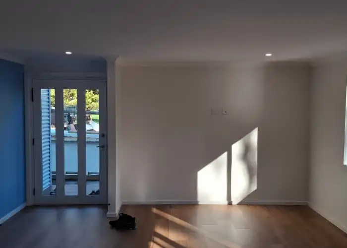 View of a home's entry and empty lounge featuring white walls, a white ceiling, and timber floors.