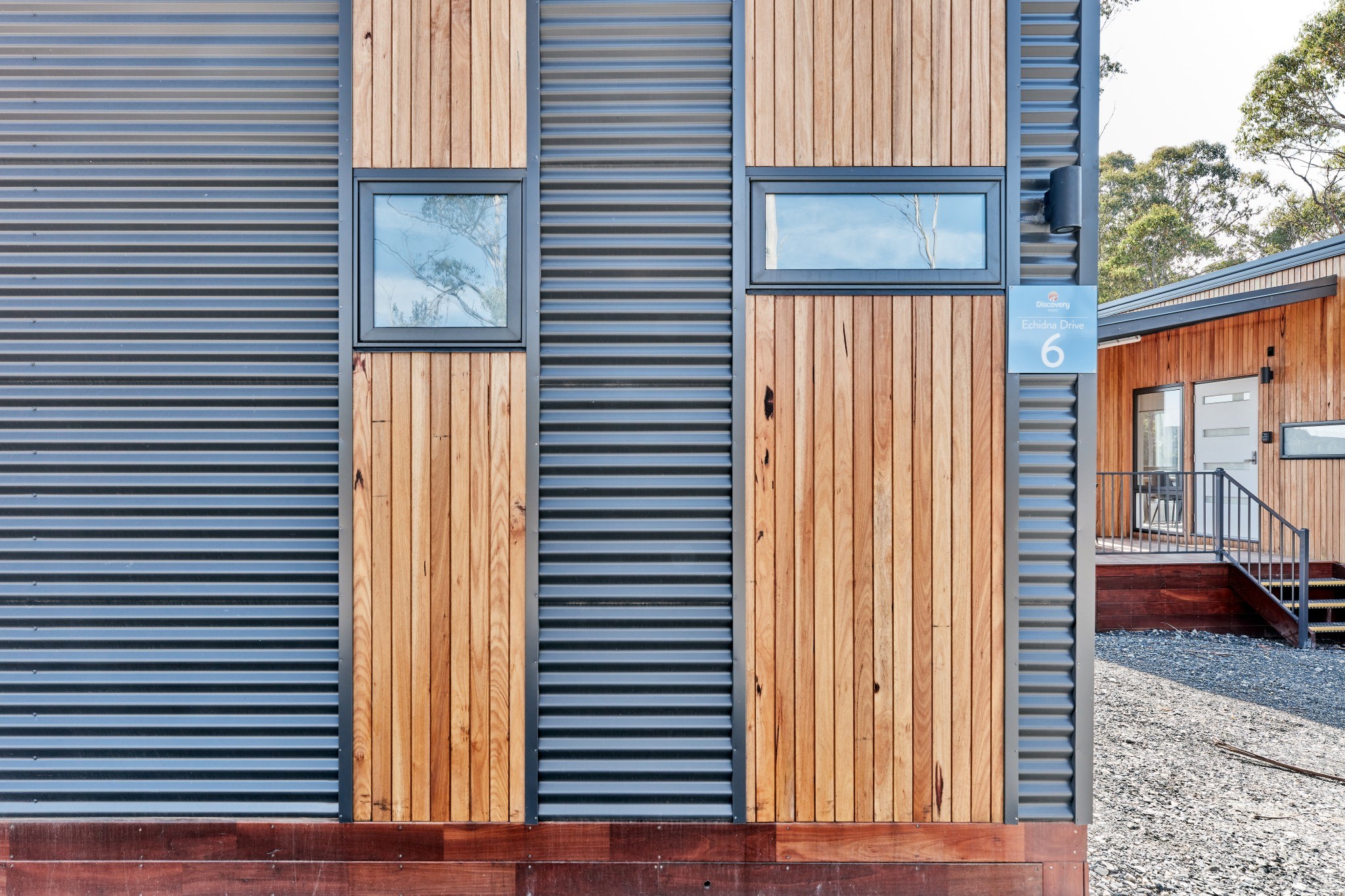 Exterior view of Tasbuilt Commercial’s luxury cabins at Discovery Park, Cradle Mountain, Tasmania, featuring colourbond and vertical timber cladding, timber decks, and a contemporary design that blends with the mountain landscape.
