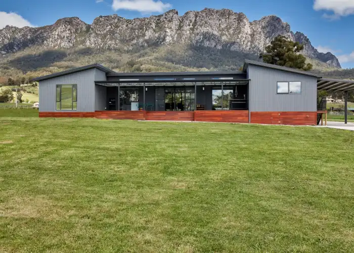 A completed home based on the Apollo design, showcasing grey vertical corrugated iron and a black feature wall with Mount Roland visible in the background.