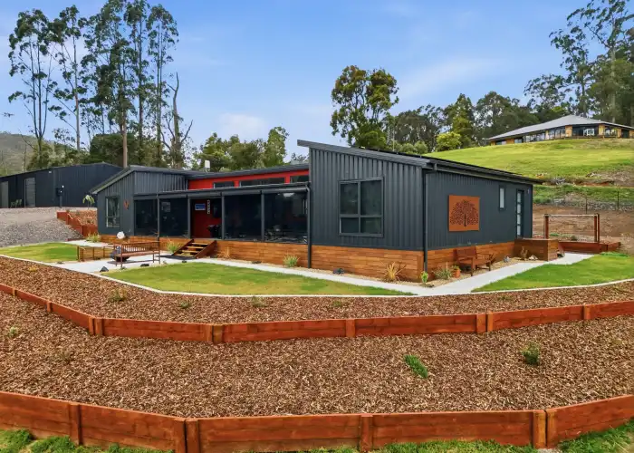 A photograph of a completed Apollo home featuring black vertical corrugated iron panels and a vibrant red feature wall.