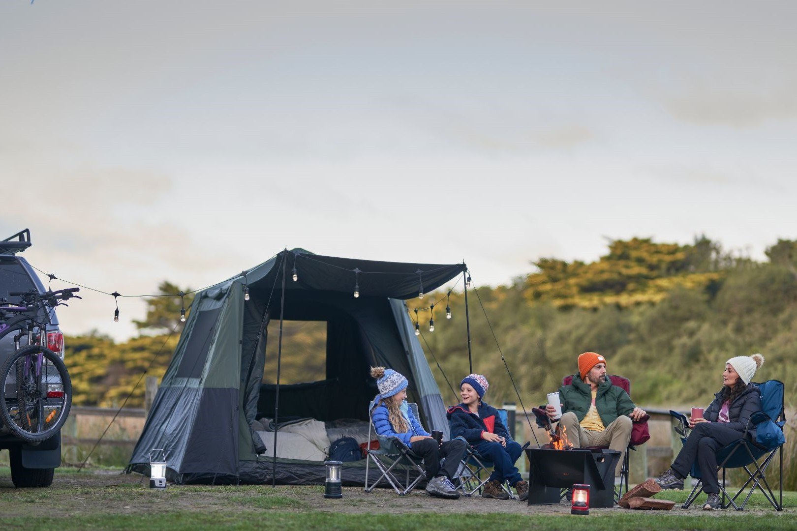 People sitting around a firepit at a campsite, reflecting how Tasbuilt Commercial creates spaces for connection.