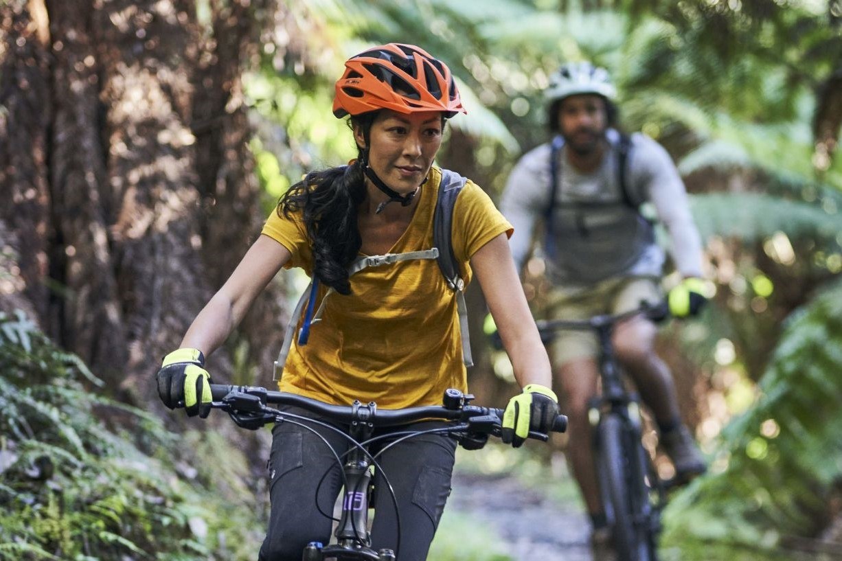 Two people riding trail bikes through a rainforest, showing Tasmania’s diverse outdoor environments.