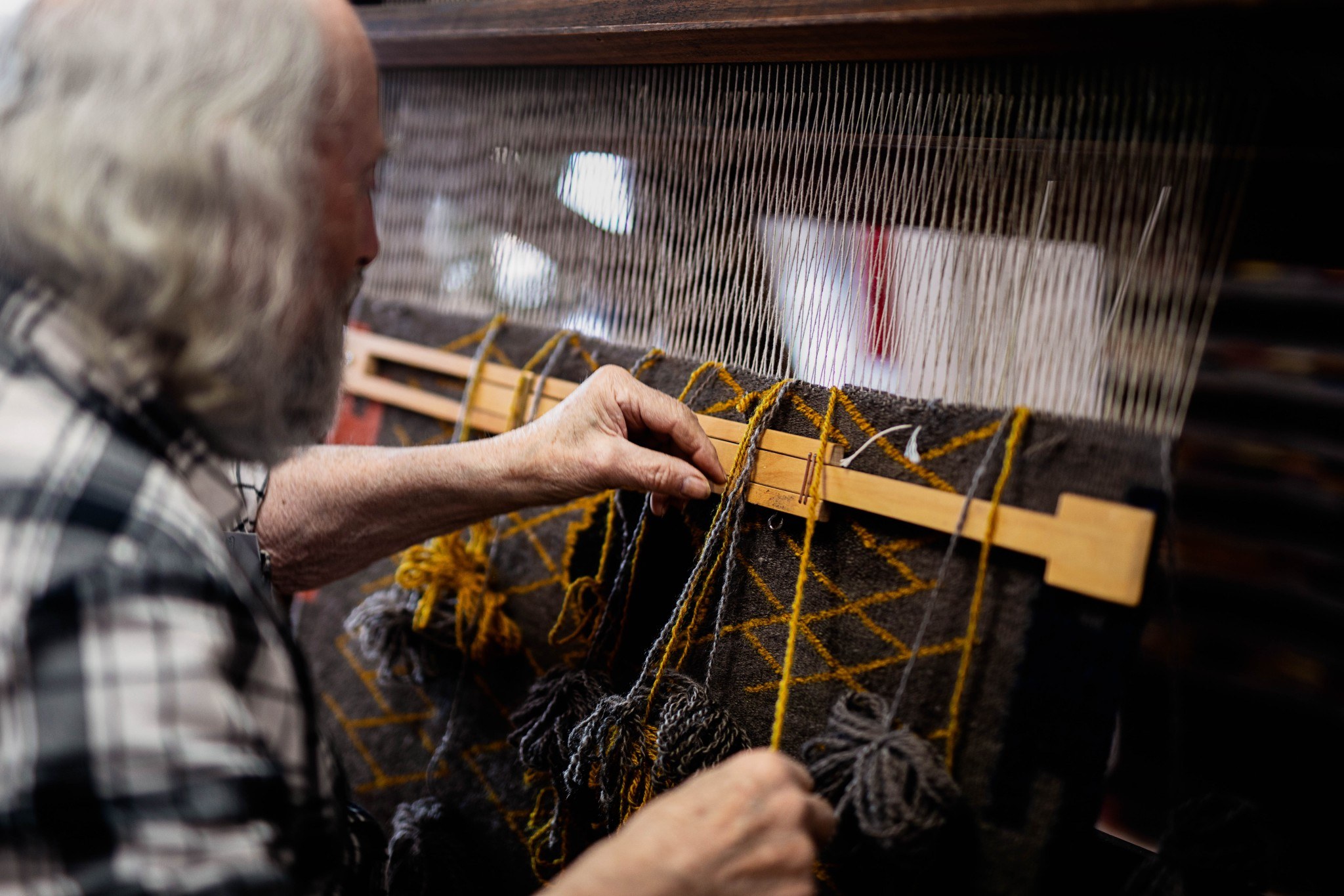 A craftsman at the Tasmanian Craft Fair in Deloraine weaving by hand using traditional techniques, showcasing local artistry.